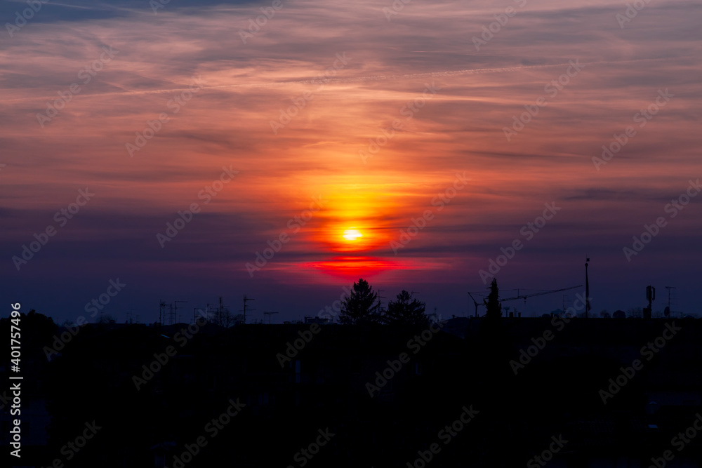 Fototapeta premium Tramonto sulla città storica fortezza di Palmanova con sagome delle case, edifici, antenne, ponteggi e bandiera.