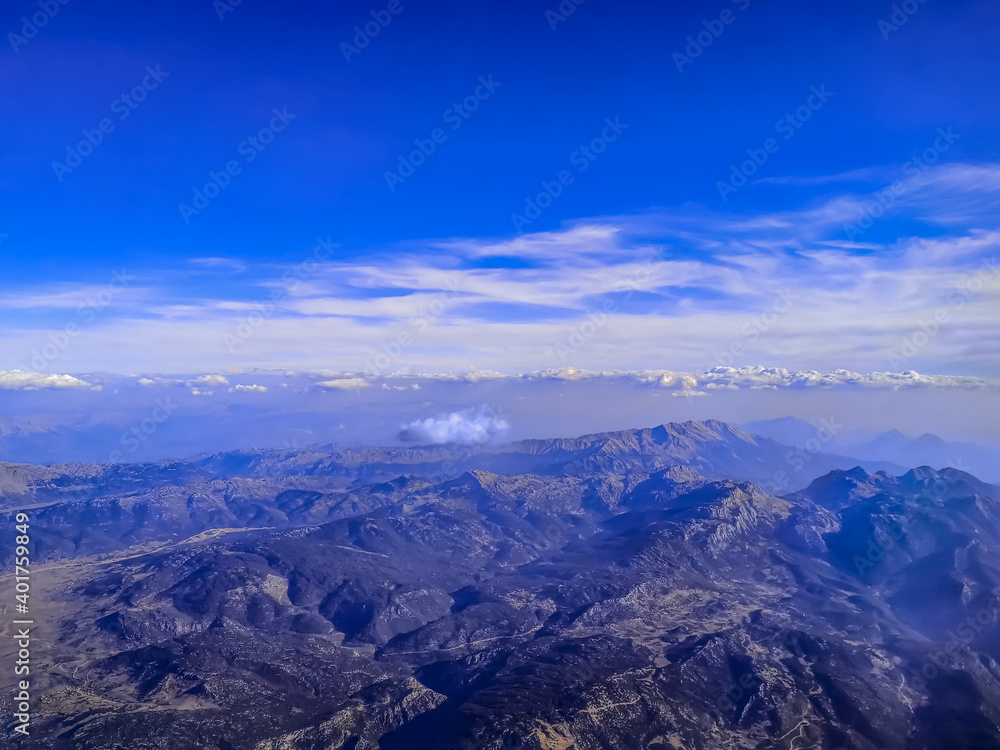 View from the airplane window on a mountain landscape in Turkey on a sunny cloudless day. Beautiful natural panorama of the peaks against the background of the blue sky and armosphere - top view