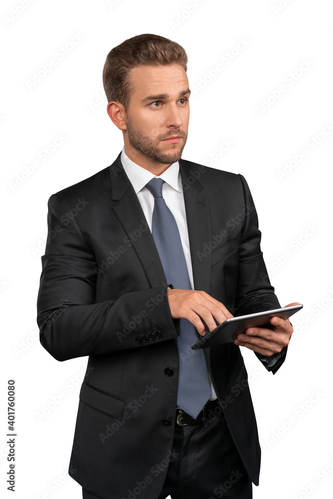 Businessman in black suit and tie standing with tablet in hands, isolated over white background. Caucasian manager pointing on the tablet, pensive look Businessman in black suit and tie standing with tablet in hands, isolated over white background. Caucasian manager pointing on the tablet, pensive look