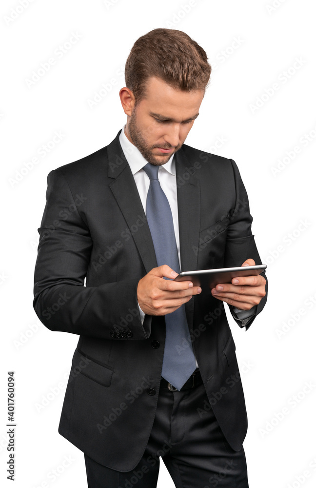 Businessman in black suit and tie standing with tablet in hands, isolated over white background. Caucasian manager looking at the tablet screen Businessman in black suit and tie standing with tablet in hands, isolated over white background. Caucasian manager looking at the tablet screen