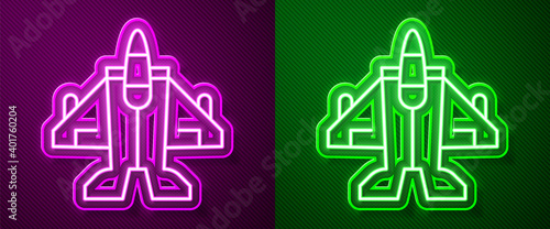 Glowing neon line Jet fighter icon isolated on purple and green background. Military aircraft. Vector.
