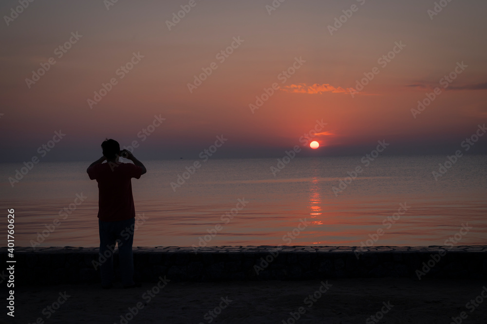 a men on the beach is taking photo on the sunshine on the sea 