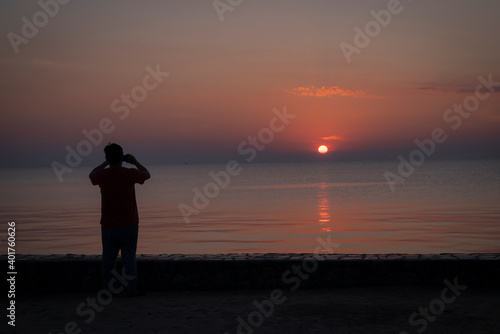 a men on the beach is taking photo on the sunshine on the sea 