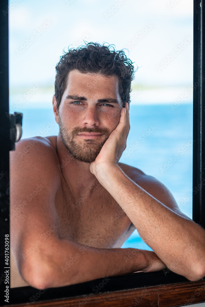 Portrait of handsome man with white teeth smile, shirtless surfer and blue ocean on background in Maldives Portrait of handsome man with white teeth smile, shirtless surfer and blue ocean on background in Maldives