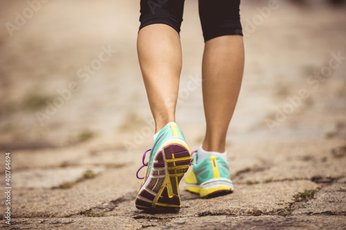 Young fitness woman hiker legs walking on trail