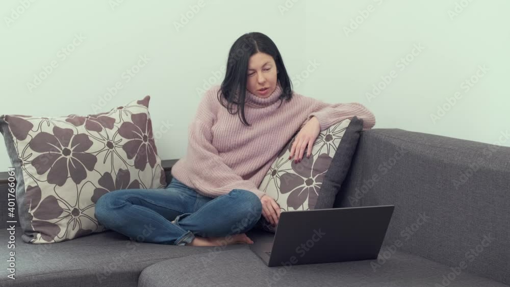 Millennial female person having video conversation while using laptop. woman smiling and talking on sofa at home. . distance online work at home. Brunette businesswoman doing freelance on the Internet Millennial female person having video conversation while using laptop. woman smiling and talking on sofa at home. . distance online work at home. Brunette businesswoman doing freelance on the Internet