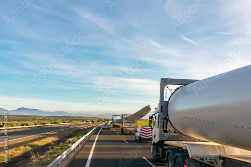 Special transport of wind turbine blades. Several trucks with wind turbine blades circulating on the highway with beacon vehicles behind to warn other road users of the danger.