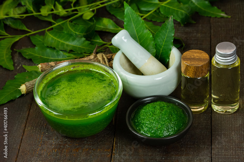 Neem leaf used as ayurvedic medicine with neem oil and stick on wooden background.