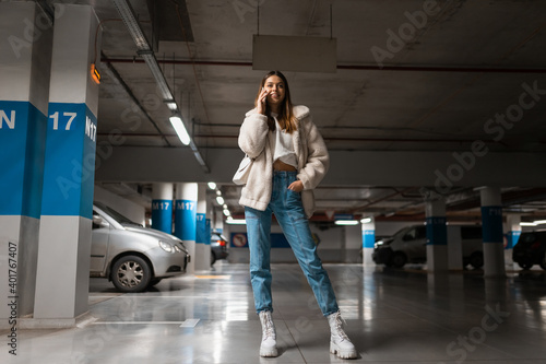 Positive fashionable girl in underground parking talking on the phone © Andrii 
