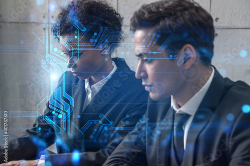 Two good looking businesspeople working together in office on IT project. Technology hologram drawings. Double exposure. Formal wear.