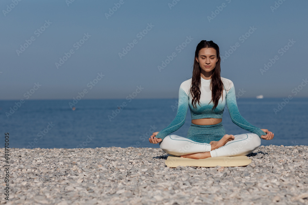 Caucasian young woman practicing yoga at seashore