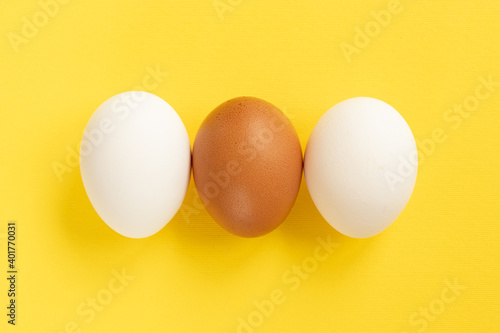 Close-up view of raw chicken eggs on yellow background.