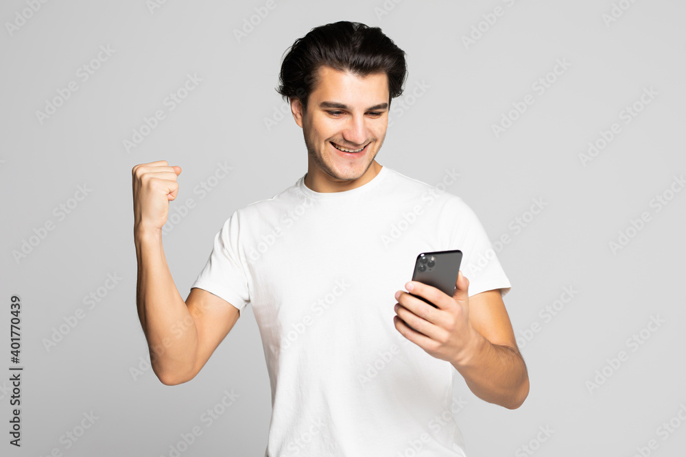 Portrait of a happy satisfied man looking at mobile phone and shouting iover white background Portrait of a happy satisfied man looking at mobile phone and shouting iover white background