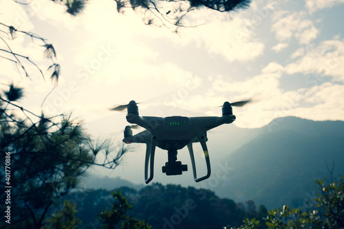 White drone with camera flying in winter tropical mountains