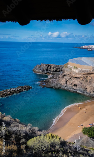  turquoise ocean breaking waves against beach and black rocks on a beautiful sunny day