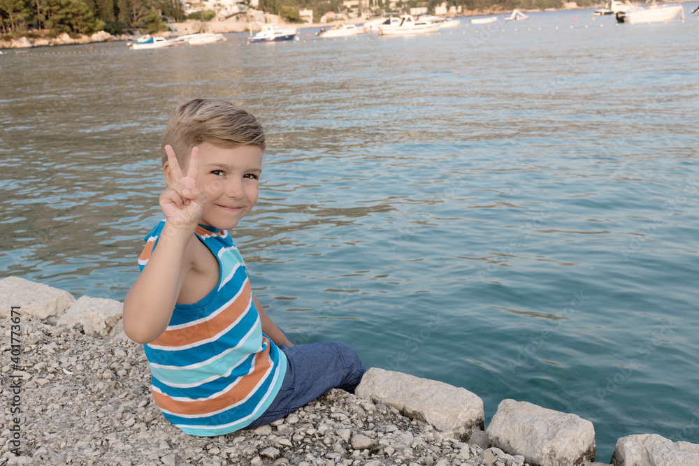 Happy kid relaxing on a pier by the sea.