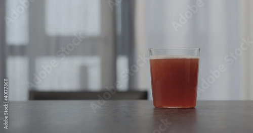 pink fizzy drink in a tumbler glass on concrete countertop with window on background