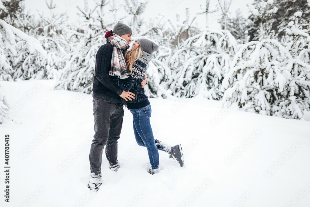 Lovers hug and look at each other against the background of a beautiful snow-covered winter forest