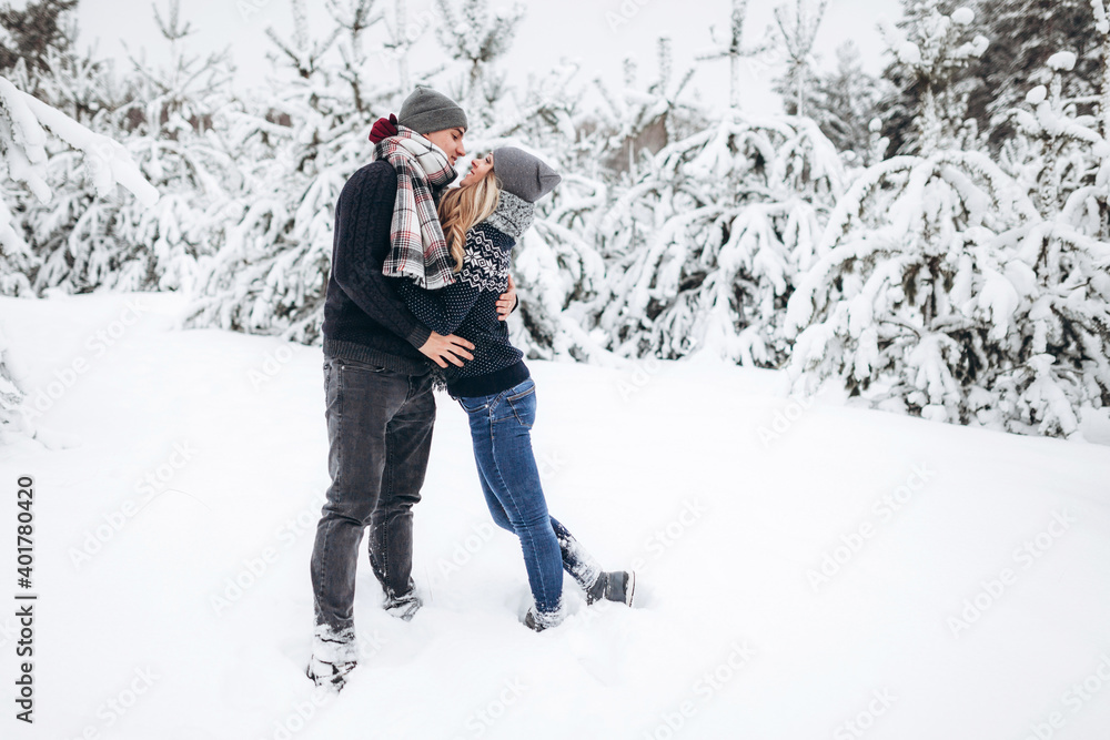 Lovers hug and look at each other against the background of a beautiful snow-covered winter forest