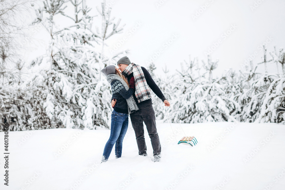 A loving couple kissing in a snowy beautiful forest in winter