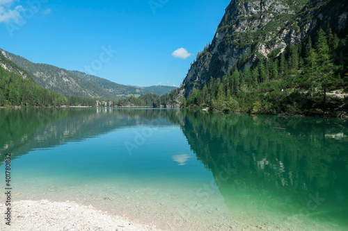 A panoramic view on the Pragser Wildsee, a lake in South Tyrolean Dolomites. High mountain chains around the lake. The sky and mountains are reflecting in the lake. Dense forest at the shore. Serenity © Chris