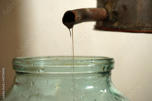 From the tube of the distillation cube flows into a jar of moonshine trickle. photo