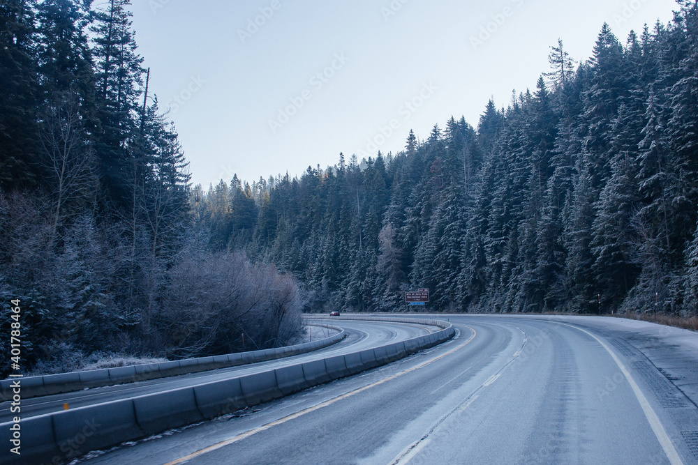 The road in winter, along which cars travel, among snow-covered trees and frost-covered roadsides. Idaho, USA, 11-23-2019