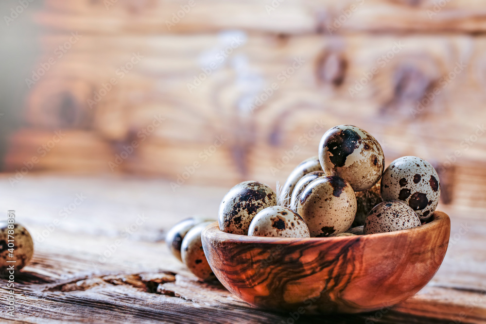 Quail fresh eggs in an olive bowl on an old wooden table. Copy space for text. Quail fresh eggs in an olive bowl on an old wooden table. Copy space for text.