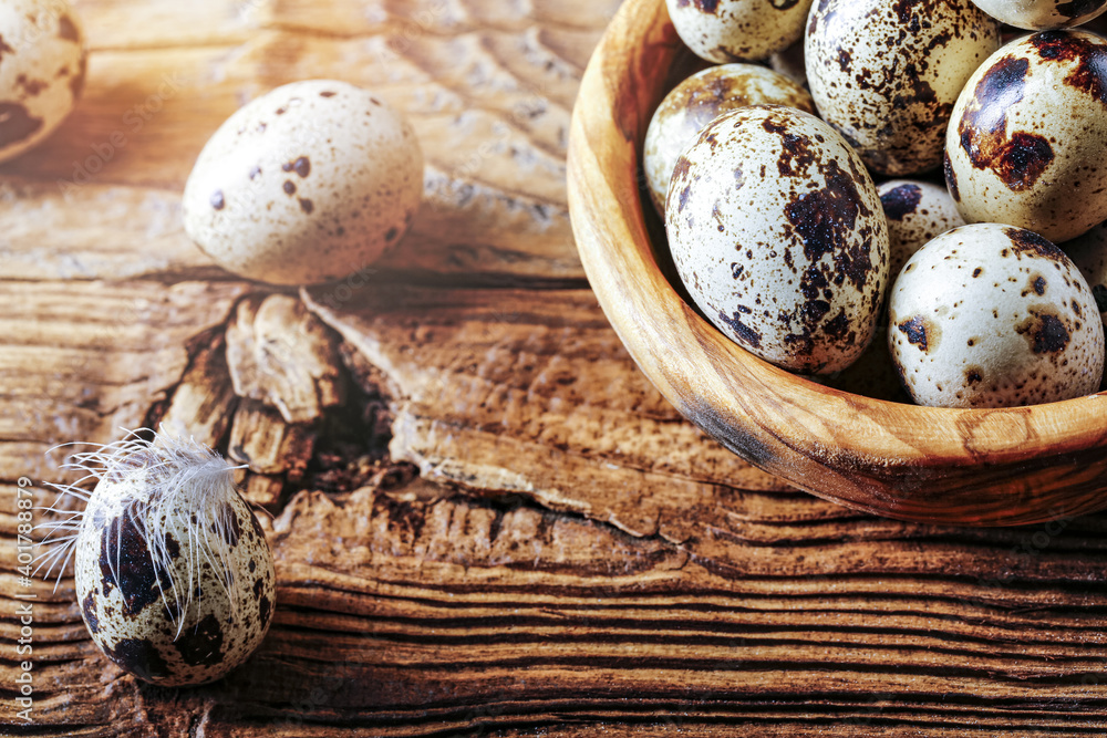 Quail fresh eggs in an olive bowl on an old wooden table. Copy space for text. Quail fresh eggs in an olive bowl on an old wooden table. Copy space for text.