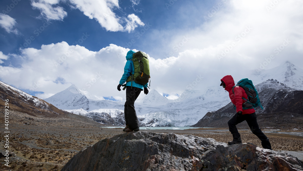 Two women hikers hiking in winter high altitude mountains