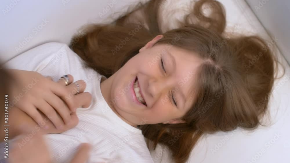 mom is tickling her daughter that are laughing on the sofa mom is tickling her daughter that are laughing on the sofa