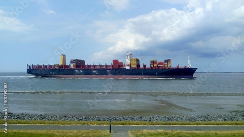 a big cargo ship is navigating along mudflats in the westerschelde sea in summer
 photo