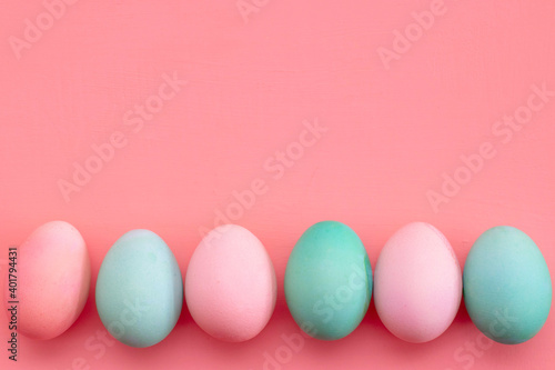 Easter decor in pastel colors: turquoise and pink eggs on a pink background, copy space. The photo
