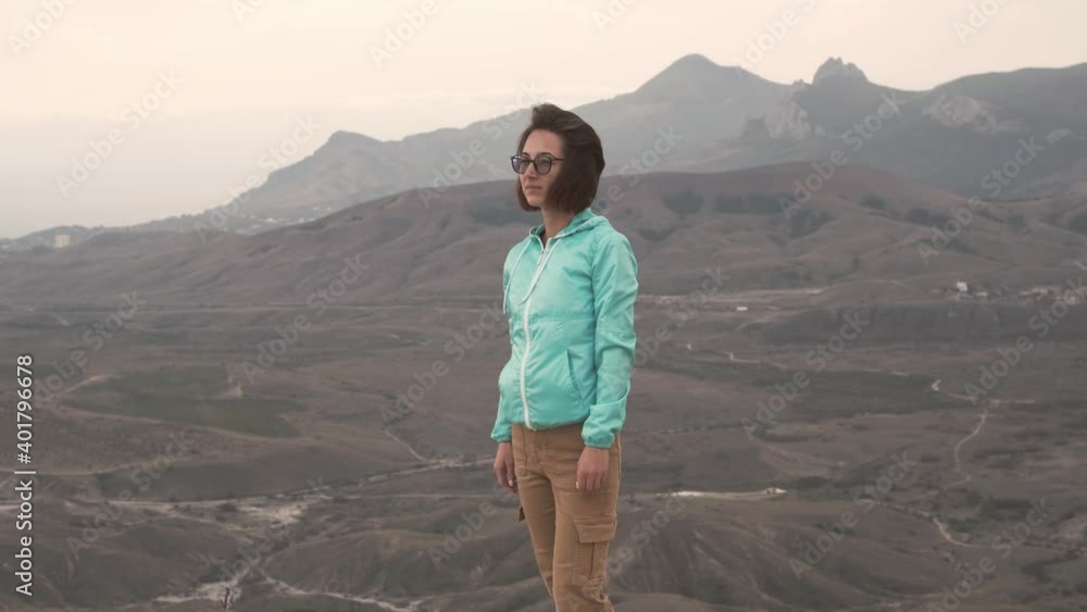Beautiful young woman enjoying view of autumn mountain valley and then looking at camera and smiling. Travel and tourism concept. Koktebel, Crimea. Beautiful young woman enjoying view of autumn mountain valley and then looking at camera and smiling. Travel and tourism concept. Koktebel, Crimea.