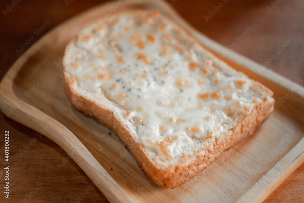 A piece of sliced bread toast with cheese served in wooden plate A piece of sliced bread toast with cheese served in wooden plate