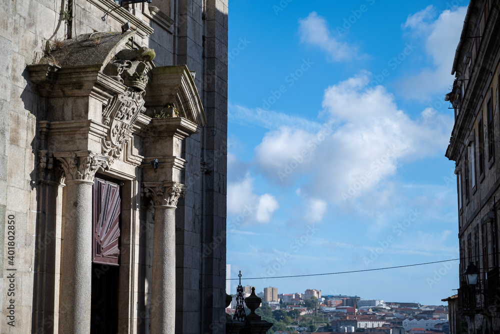 Facade of the Igreja Paroquial de Nossa Senhora da Vitória (Parish Church of Nossa Senhora da Vitória). Details worked in stone. City in the background. Blue skie with clouds.