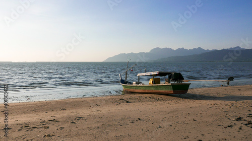 Fototapeta Naklejka Na Ścianę i Meble -  Traditional fishing boat by the beach with view of mountain on bright sunny day.