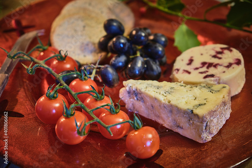 Orange winter platter of cheeses, black grapes and vine tomatoes