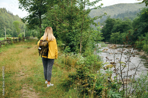 The beautiful girl traveler walks through the village. Beautiful nature landscape in countryside. Hiking journey on tourist trail. Outdoor adventure. Travel and exploration. Healthy lifestyle © Iuliia Pilipeichenko