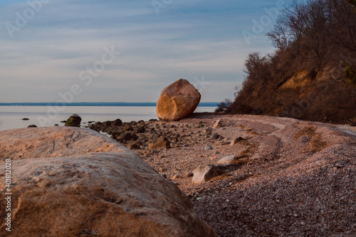 Seashore filled with seashells and rock in the evening during sunset.