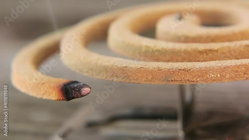 Mosquito spiral. Burning mosquito coil on metal stand.  A green mosquito spiral smokes outside. Mosquito repellent coil