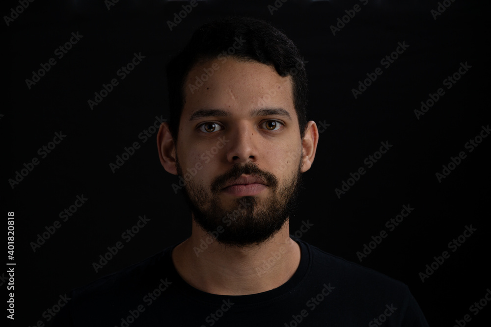 Closeup frontal portrait of young men serious over black background.