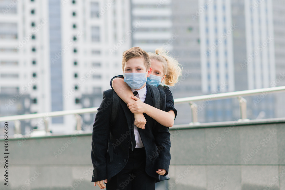 Schoolchildren, a boy and girl in medical masks walk in the city. Schoolchildren, a boy and girl in medical masks walk in the city.