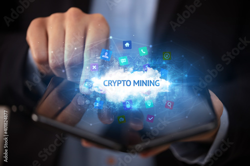 Businessman holding a foldable smartphone with CRYPTO MINING inscription, technology concept