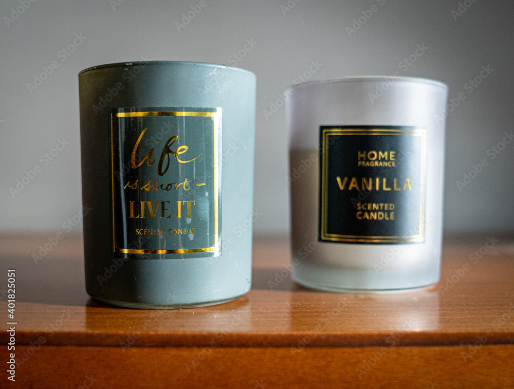 Set of two glass candles on a wooden furniture turquoise grey white and brown during golden hour with motivational sayings about life

