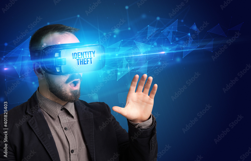 Businessman looking through Virtual Reality glasses with IDENTITY THEFT inscription, cyber security concept Businessman looking through Virtual Reality glasses with IDENTITY THEFT inscription, cyber security concept