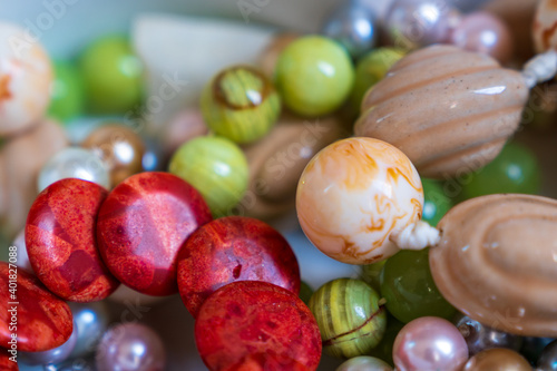 Mixed jewellery box including blood orange coral stone bracelet, green grape agate bracelet, multi-colored pearl necklace and cream ceramic necklace 