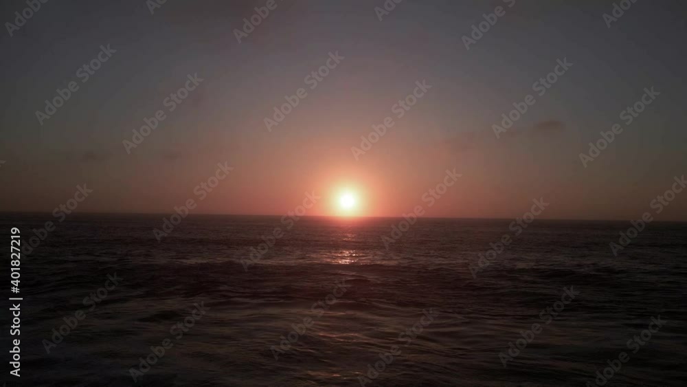 Flying low over dark rolling waves reflecting golden hazy sunlight, aerial sunset Flying low over dark rolling waves reflecting golden hazy sunlight, aerial sunset