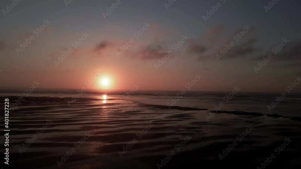 Small silhouetted tidal pools reflect the warm hazy golden sunset light, aerial dolly Small silhouetted tidal pools reflect the warm hazy golden sunset light, aerial dolly