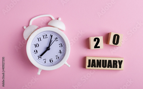 On a pink background, a white alarm clock and wooden cubes with the date of JANUARY 20